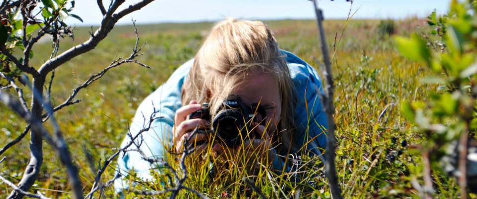 girl lying on grass holding camera