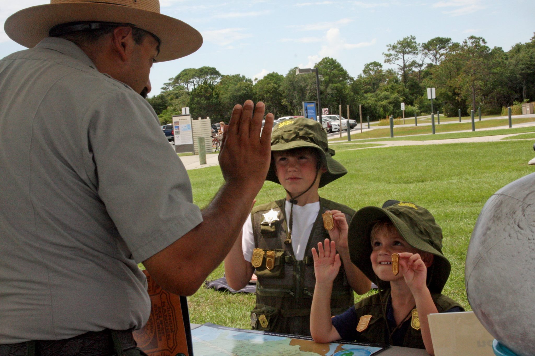 Two children wearing JUnior Ranger vests get their badge pinned by a ranger.