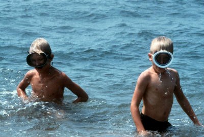 Two boys with face masks play in the water.