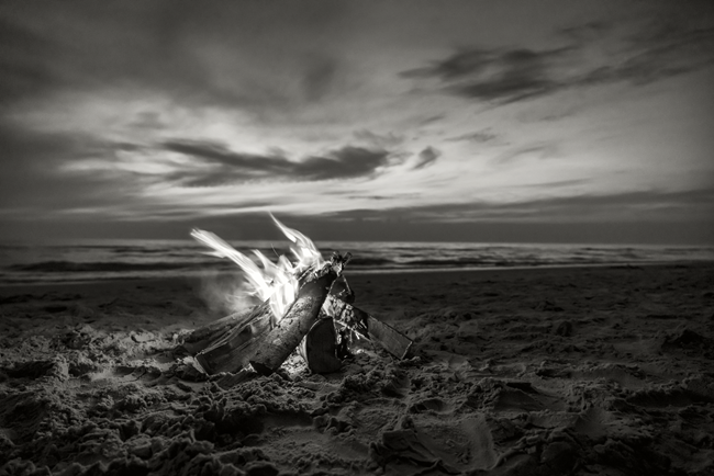 Campfire on sandy beach by the water