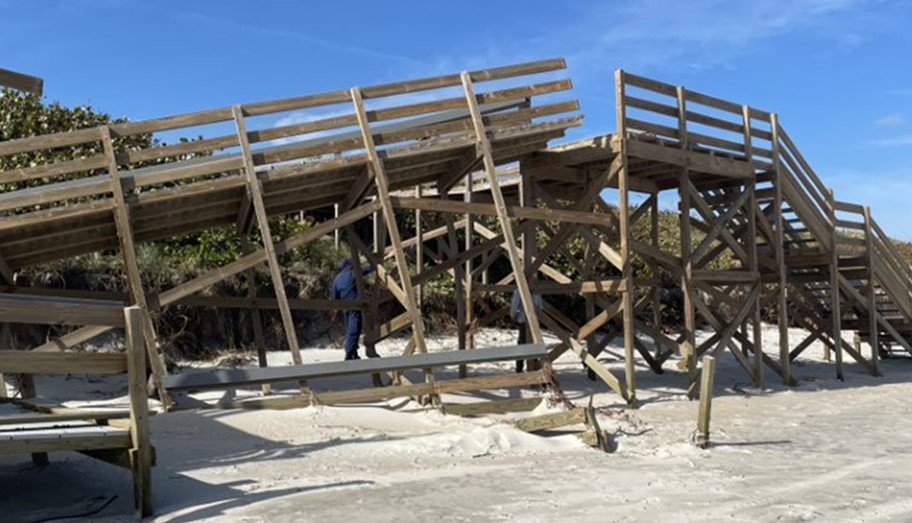 A beach boardwalk is broken in half.