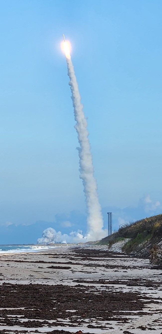 Rocket shooting off with the beach and the sky around it