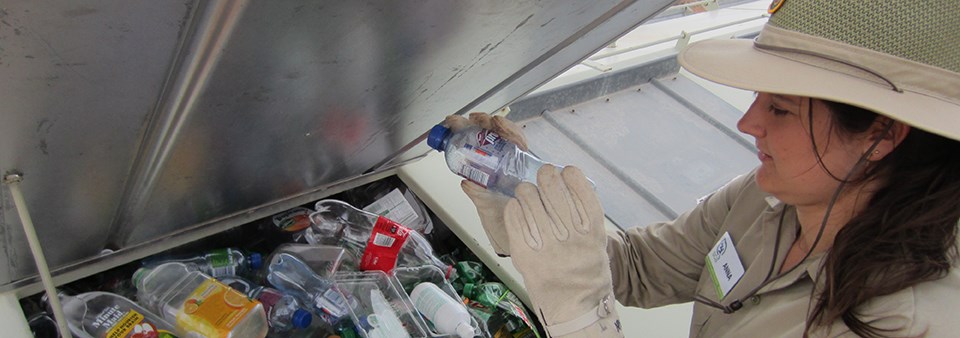 a woman puts plastic bottles into a recycling container