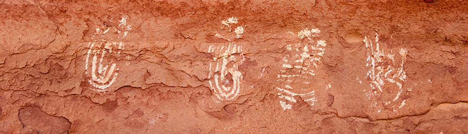 A rock surface with white, hand-shaped paintings on it