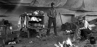 a cowboy stands among shelves and a campfire