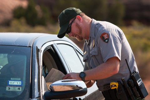 a park ranger talks with someone sitting in a car