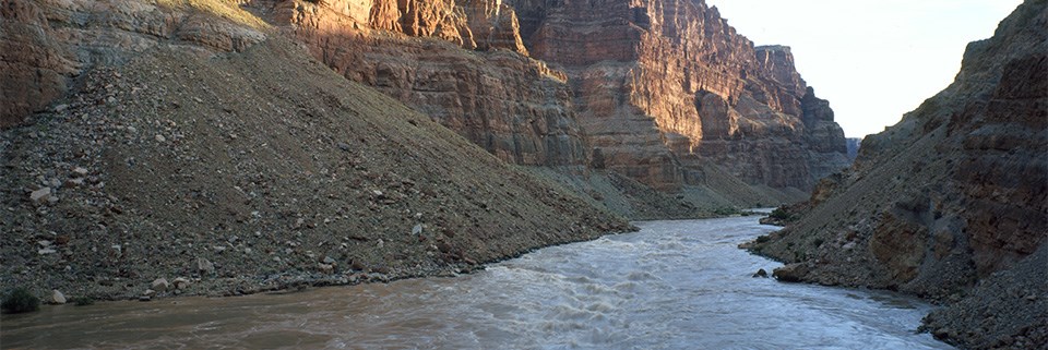 The Colorado River flows in a canyon with high cliffs.
