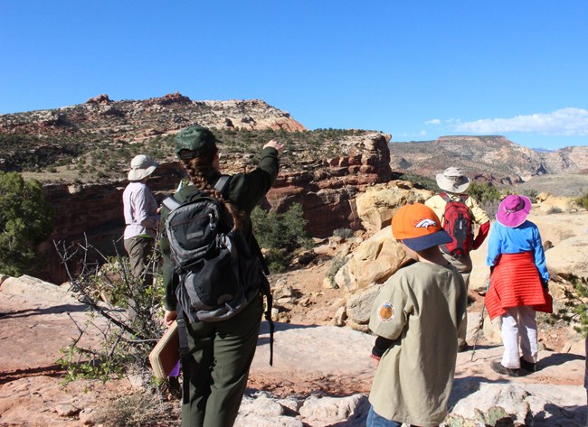 A ranger and visitors at a viewpoint on the Hickman Bridge trail