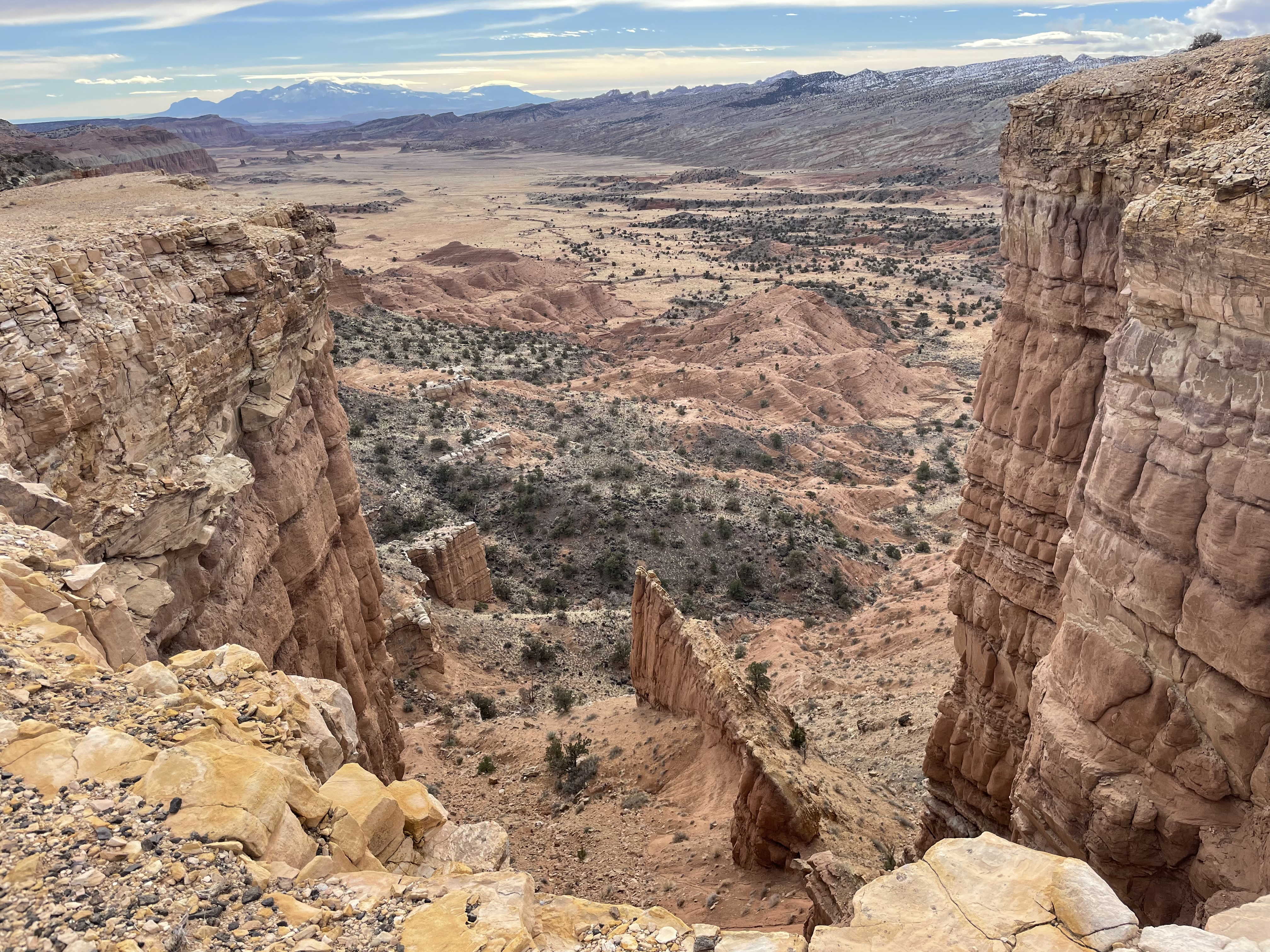 Sandstone cliffs frame a view down into a desert valley.