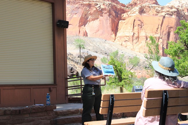 A ranger holds an image up to visitors during a program