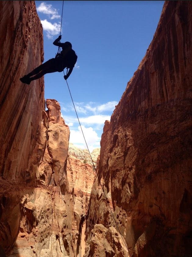 A person rappelling into a canyon