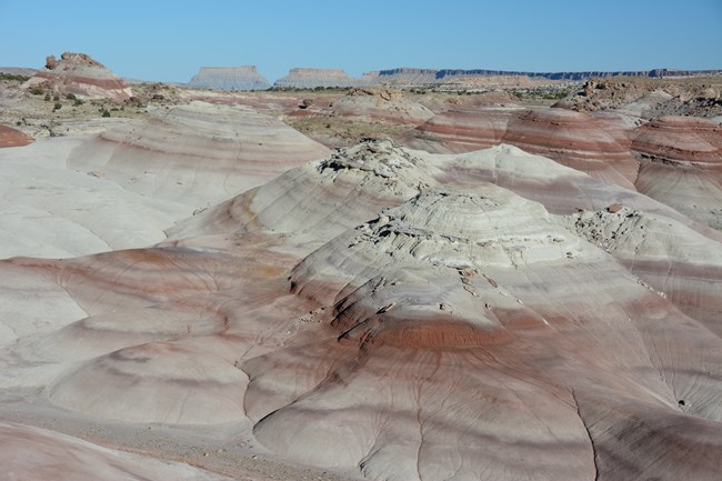 Soft gray, maroon, and purple rock layers in sloping hills