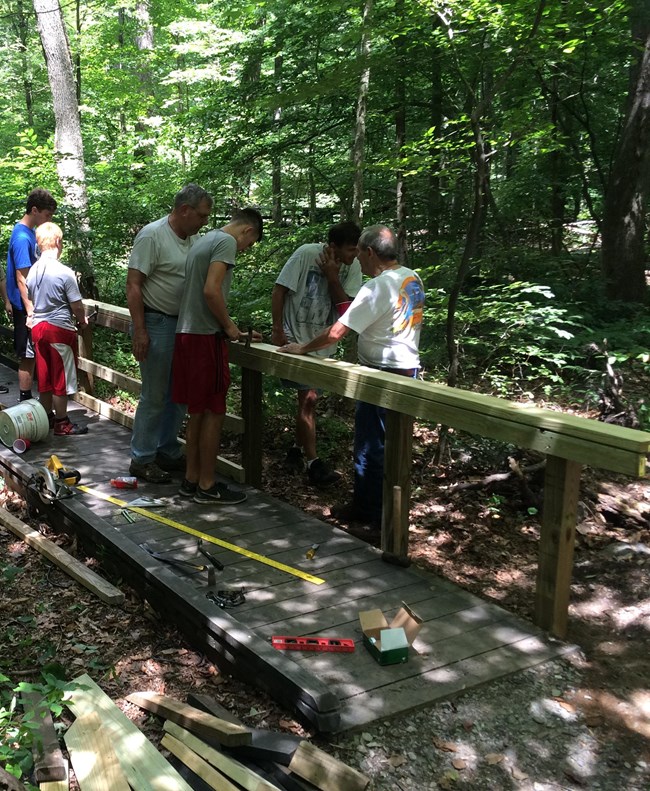 Scouts installing railing onto wooden boardwalk