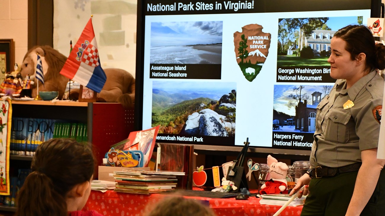 A park ranger listens to students while presenting in a school library.