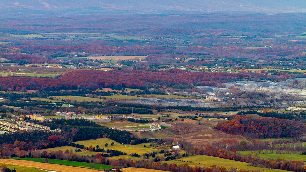 A mountain view shows a valley of farms, residences, and industry.