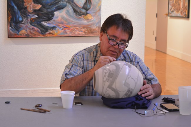An artist works at applying designs to pottery