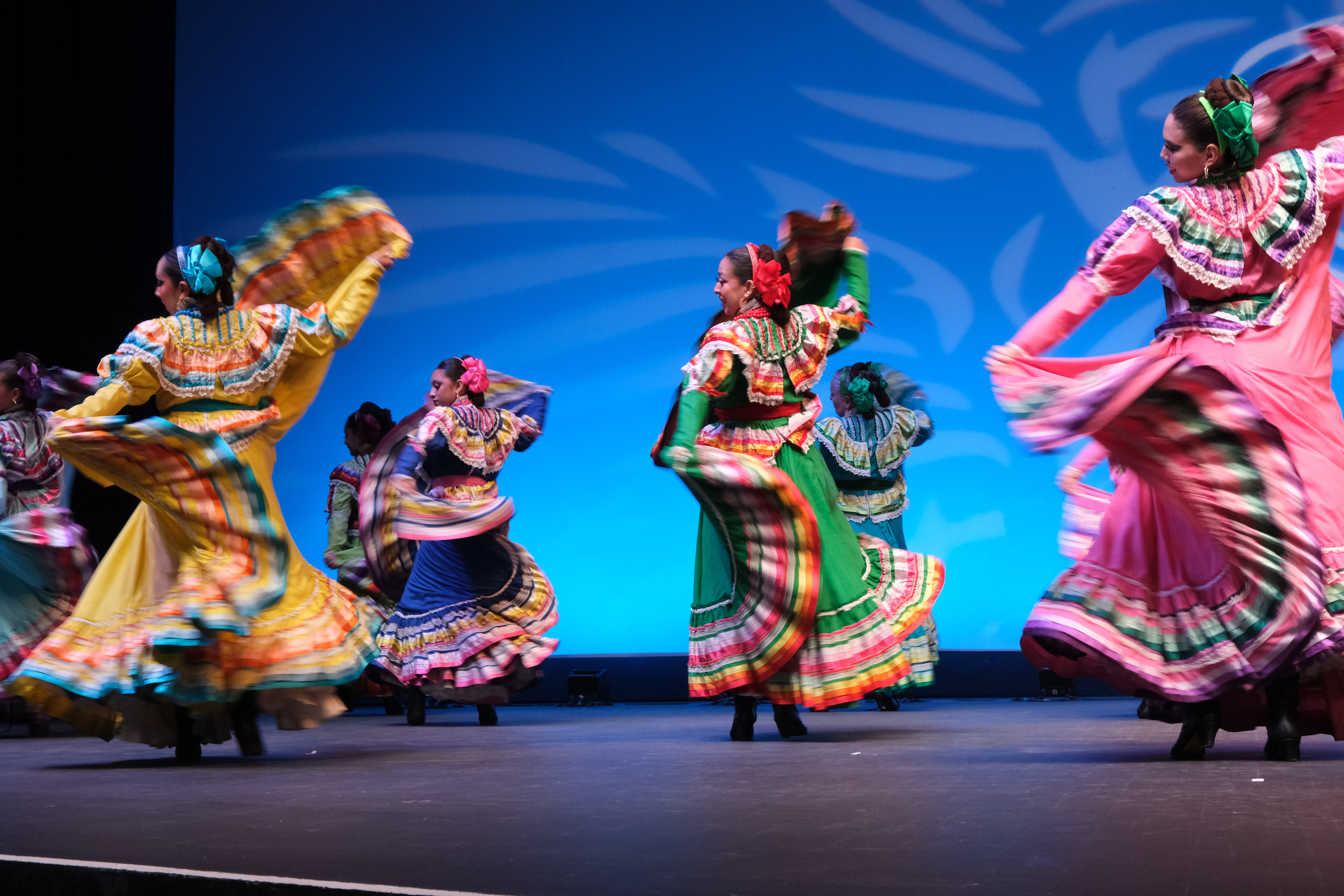 Folklorico dancers in brightly colored dresses perform on stage
