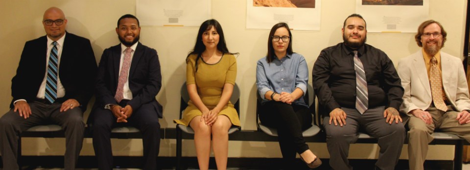 six people in regular dress clothes sitting in a row of chairs