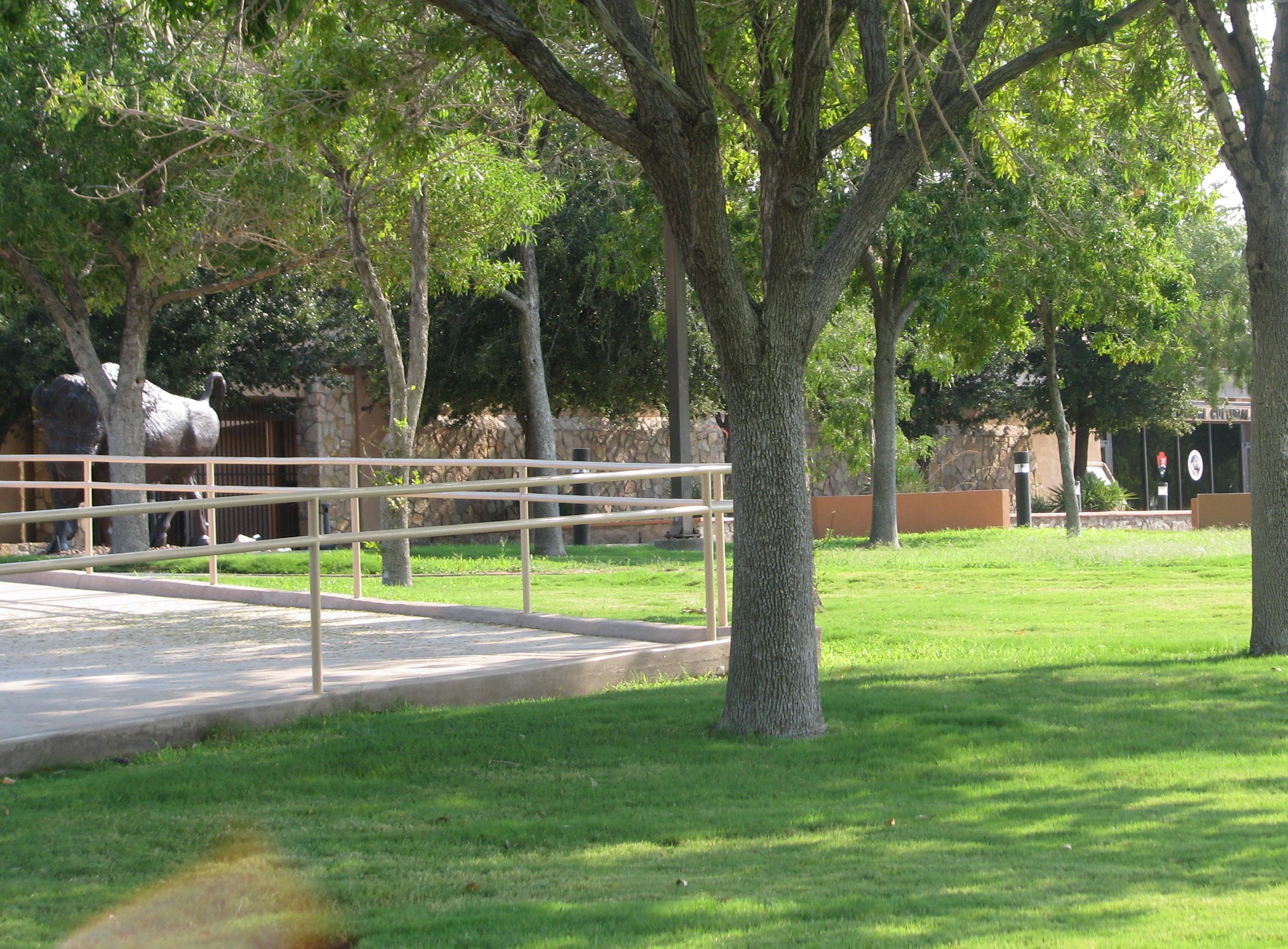 Showing paved sidewalk, ramp and handrails in front of cultural center.
