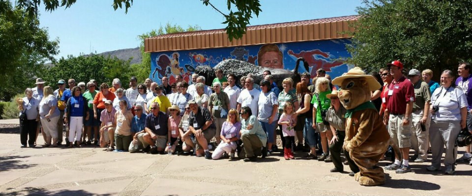 A large group of people pose for photo with squirrel mascot.