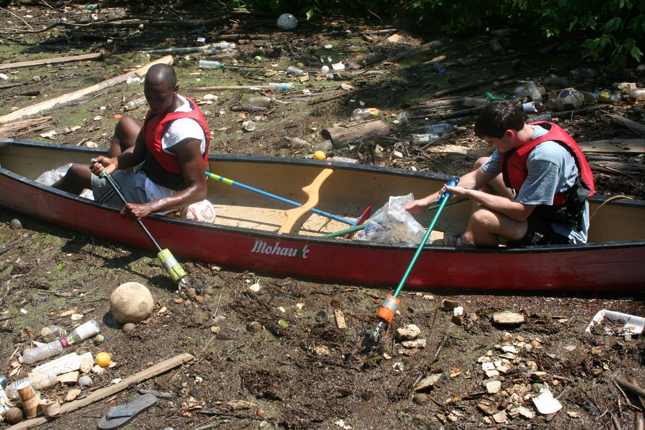 Two paddlers in canoe picking trash out of the Chattahoochee River.