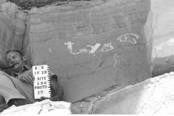 A man sitting next to a petroglyph panel.