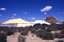An tent in a field showing Fajada Butte in the background.