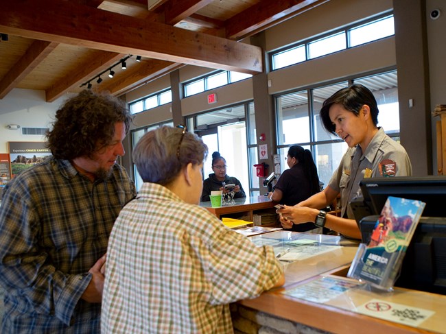 A ranger speaking with visitors at a front desk area.