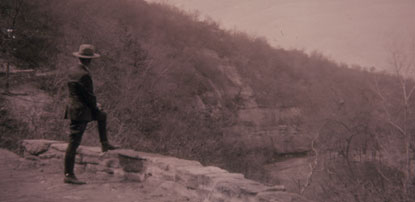 Old photo of a park ranger standing on a trail, looking into the distance