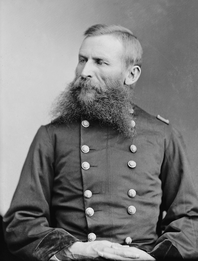 Black and white portrait of a man with a beard wearing a double-breasted coat.