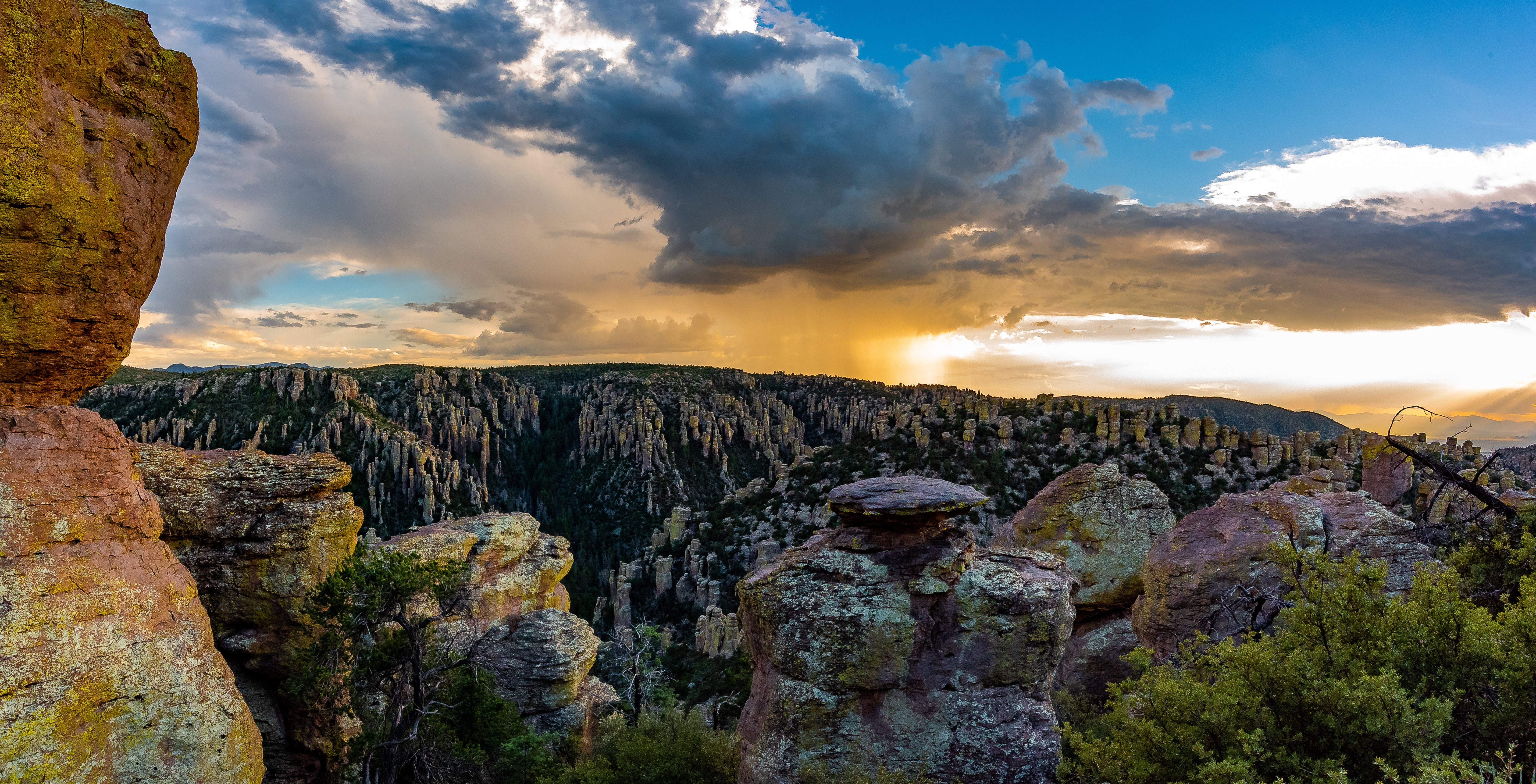 Rock pinnacles filling a valley, with blue sky and storm clouds in the background.