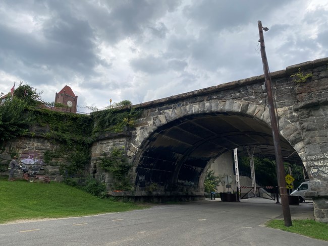 A paved road runs underneath a stone archway