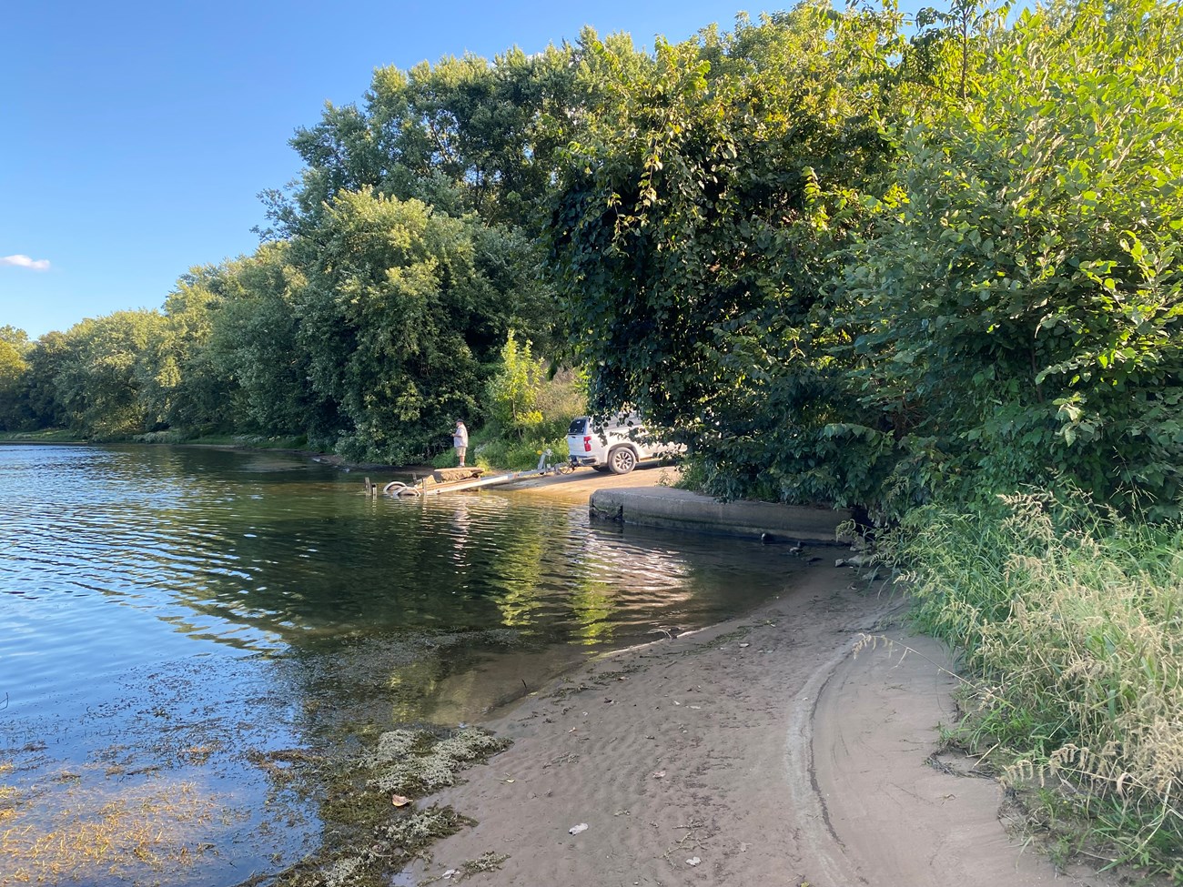 A concrete boat ramp sits along the river bank