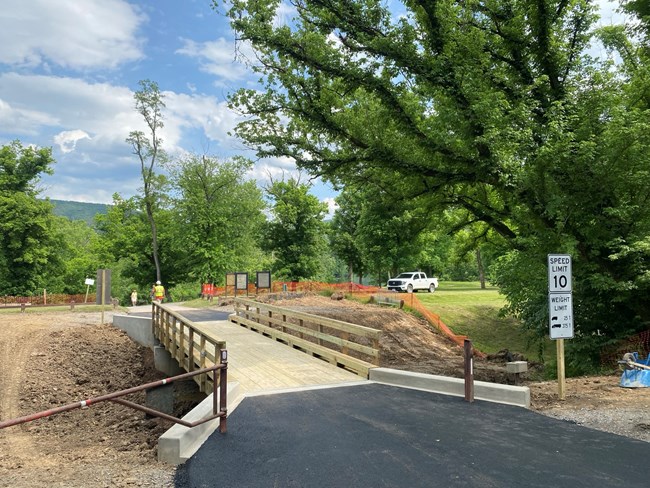 A wooden vehicle bridge spans a dry canal