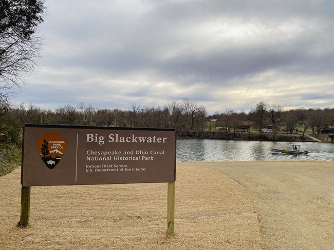A brown sign with the words "Big Slackwater" sits in front of the Potomac River