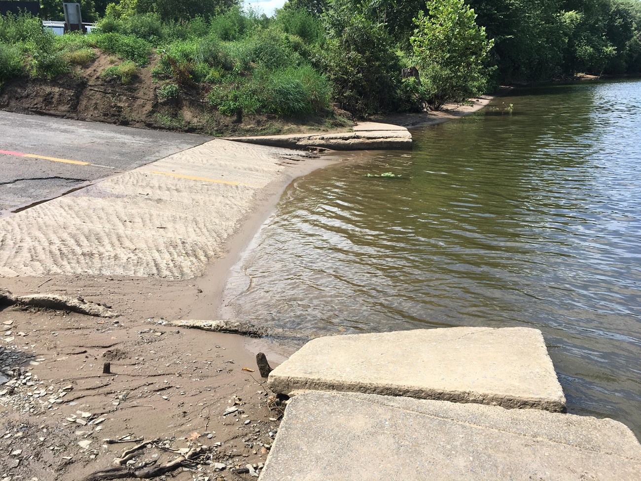 A damaged concrete boat ramp leading out to the river.