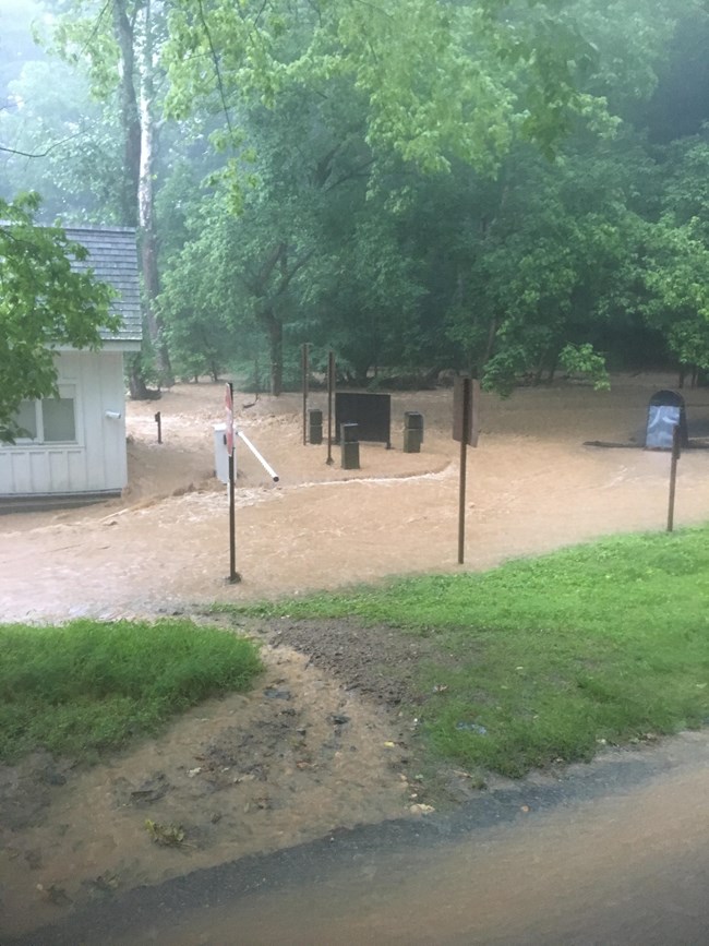 Muddy brown flood waters flow around a white building