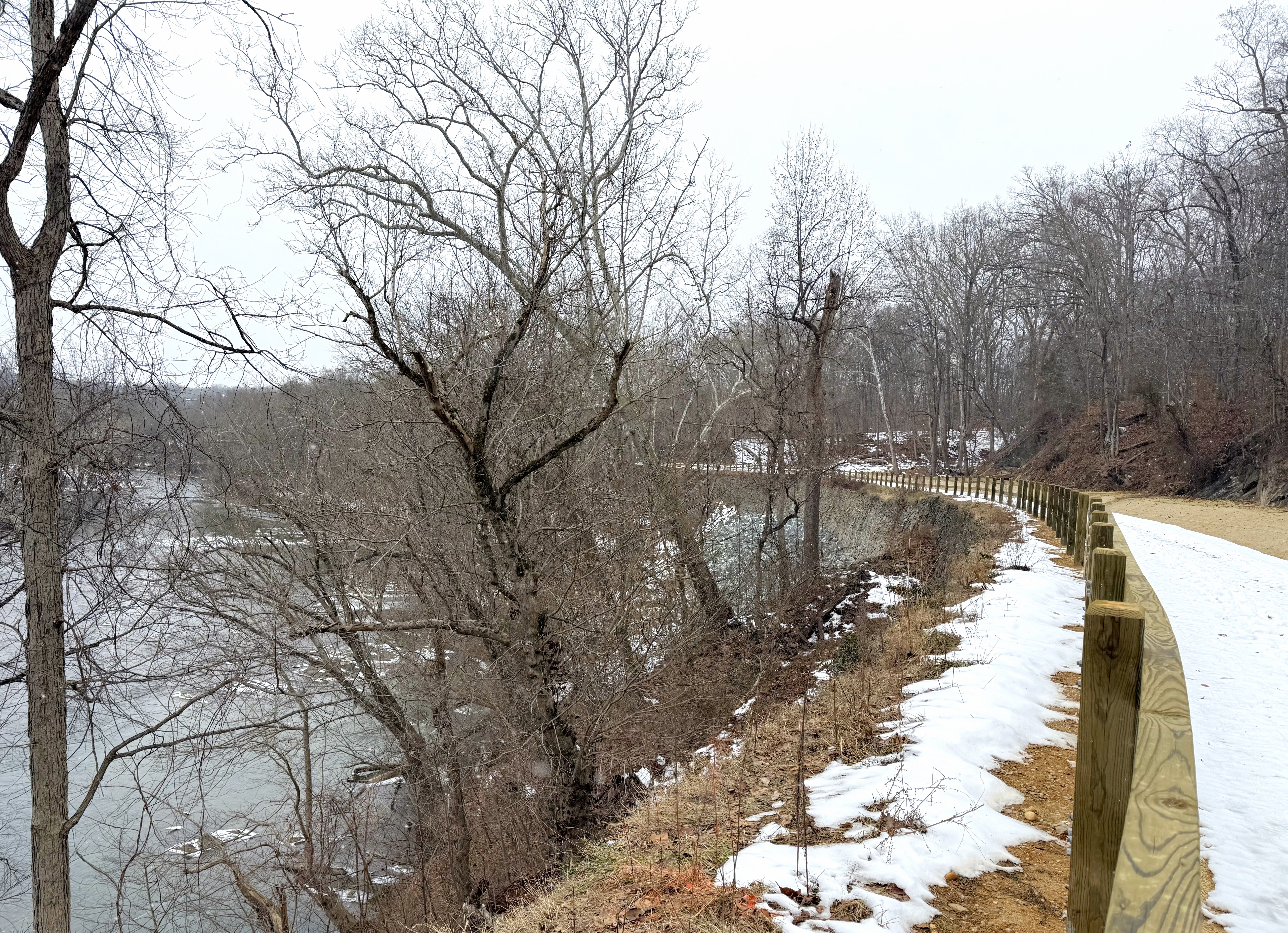 A snow-covered pathway with a large stone wall to the left