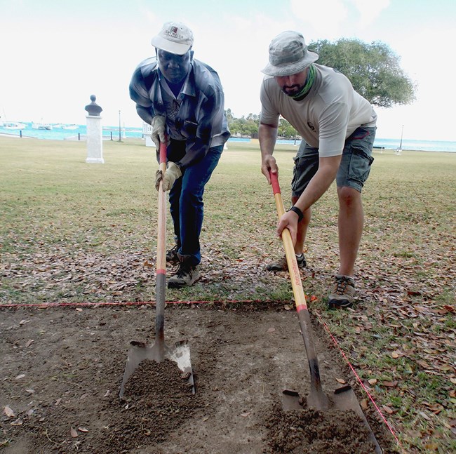 Photo of two archeologists excavating an archeological unit at Christiansted