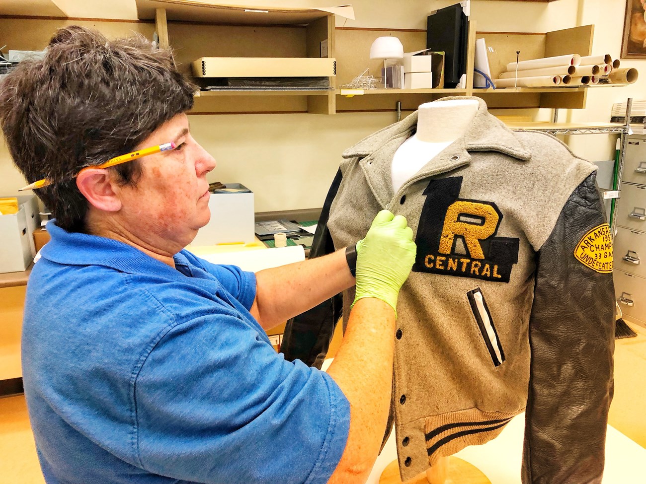 A volunteer works on the preservation and presentation of a Central High letter jacket from the 1950s.