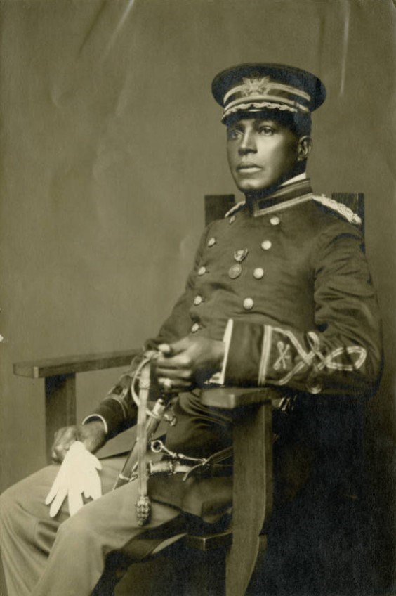 Black and white photo of Charles Young in 1910s style military uniform. He is sitting in a chair looking to the left of the viewer.