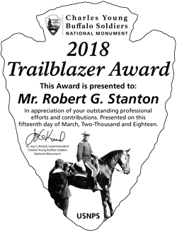 Picture of an award in the shape of an arrowhead with text and a photo of a man on a horse on it