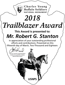 Picture of an award in the shape of an arrowhead with text and a photo of a man on a horse on it