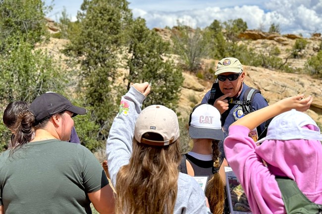 students raise hands as ranger looks inquisitively towards group outdoors