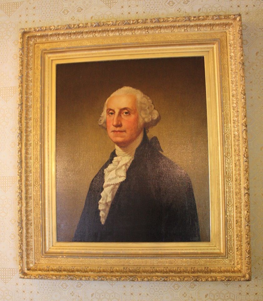 A painting of General George Washington. He is an older white gentleman with a powdered wig and stately nose.