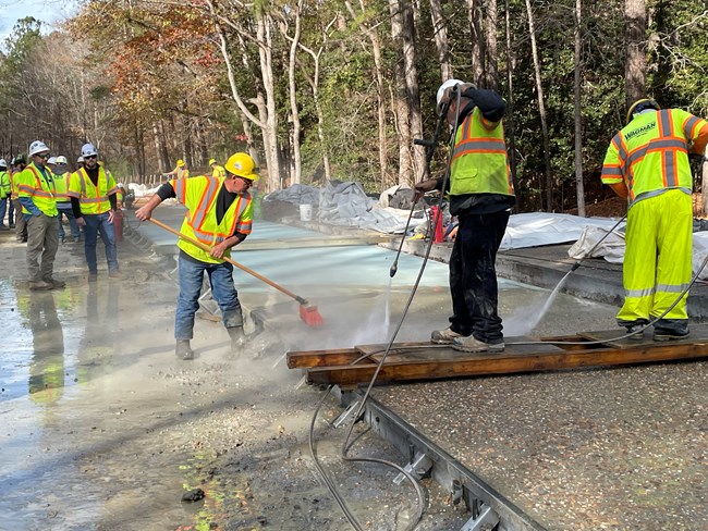 Road Surface Crew spraying water to expose concrete