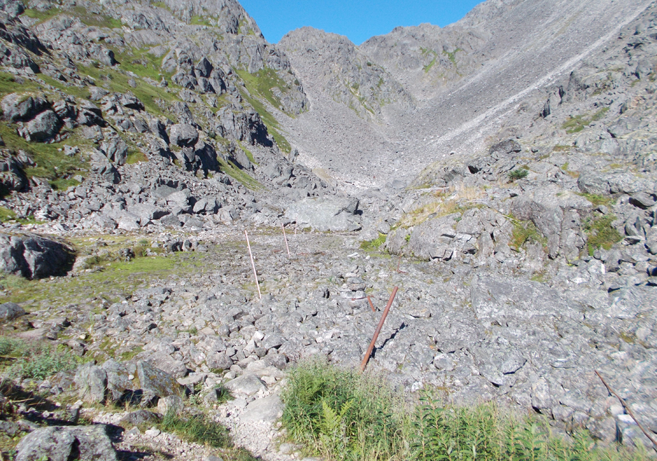 Looking across a rocky area a mountain pass with clear blue skies