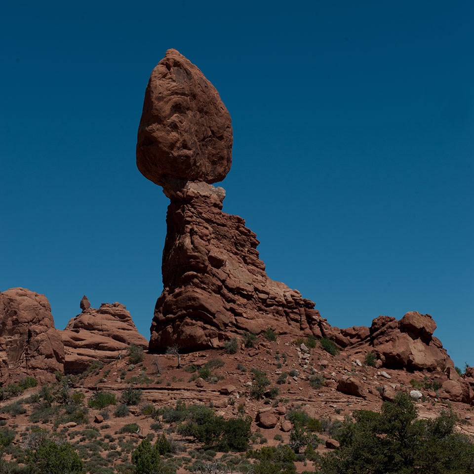 A massive rock perched on a smaller pedestal. A smaller pinnacle stands to the right.