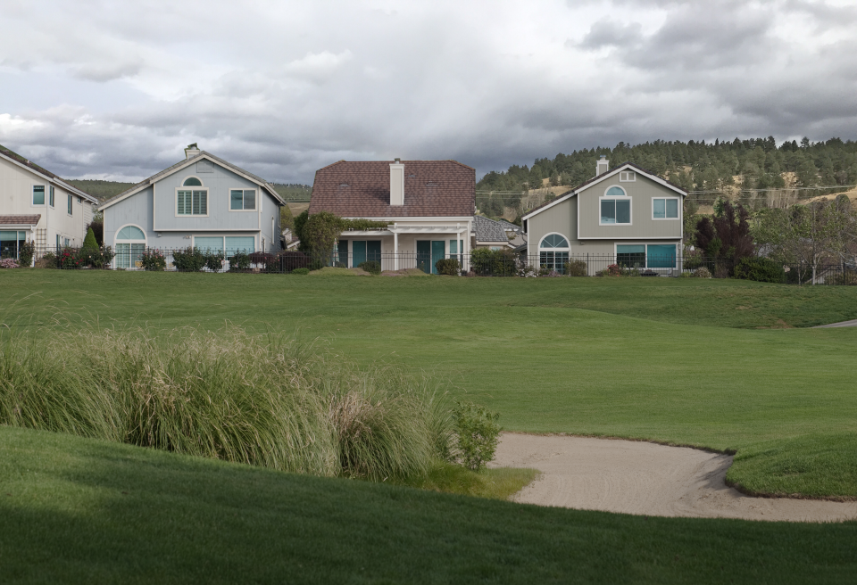 A view of a grassy valley with a tree-covered hill in the distance.