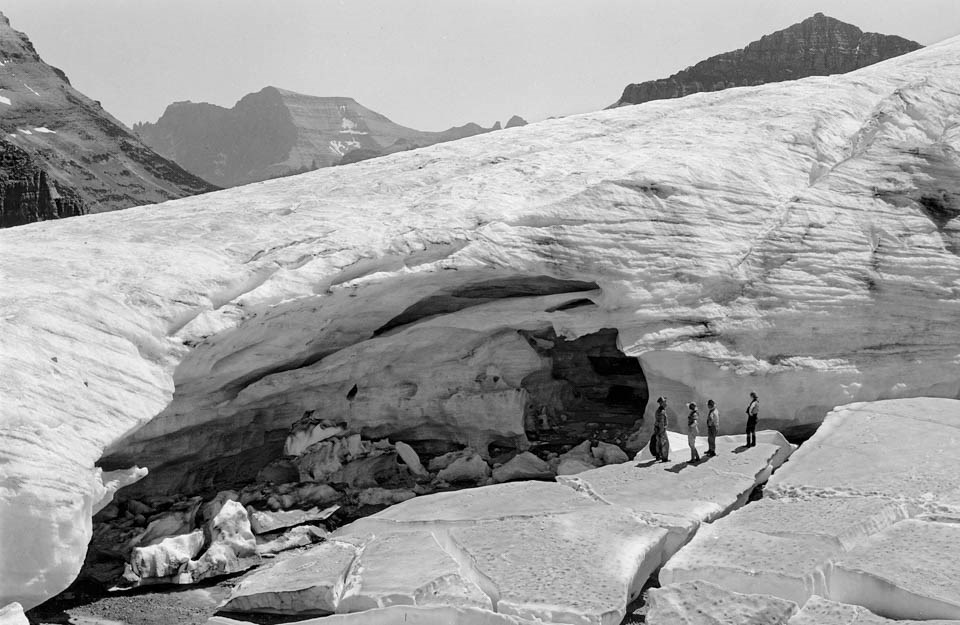 A glacier with people standing on and around it.